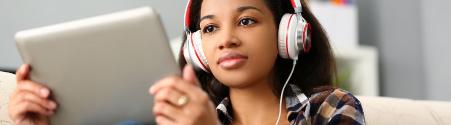 An image of a student with a tablet, listening to university videos