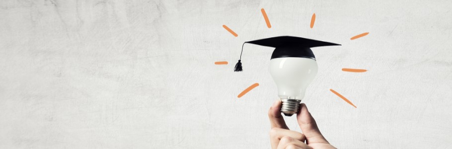 Image of a lightbulb, with a graduation hat on, being held by a student