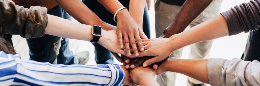 An image of a group of students with hands joined together. 