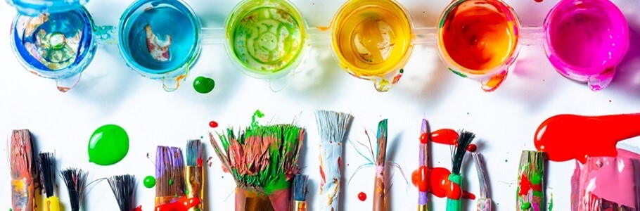 A selection of paint brushes in a line opposite a row of paint pots.