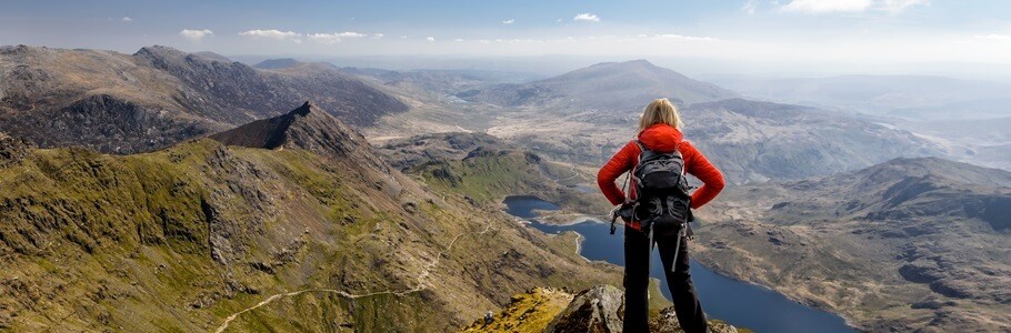 A student stands proudly overlooking a Welsh mountain range.