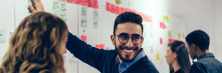 A student placing a sticky note on a whiteboard during their degree apprenticeship.